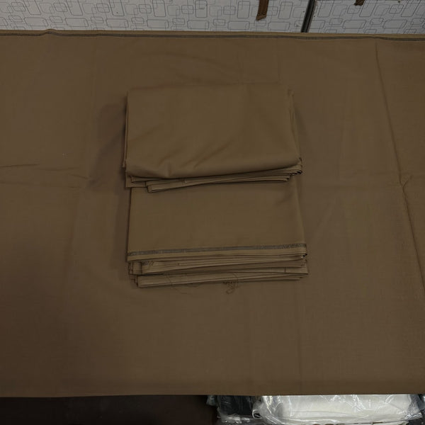 A stack of folded brown fabric, likely table linens or napkins, placed on top of a larger matching brown sheet or mat on a table.
