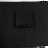 A folded black fabric item, likely a tablecloth or napkin, placed on top of a larger black tablecloth, photographed from above.